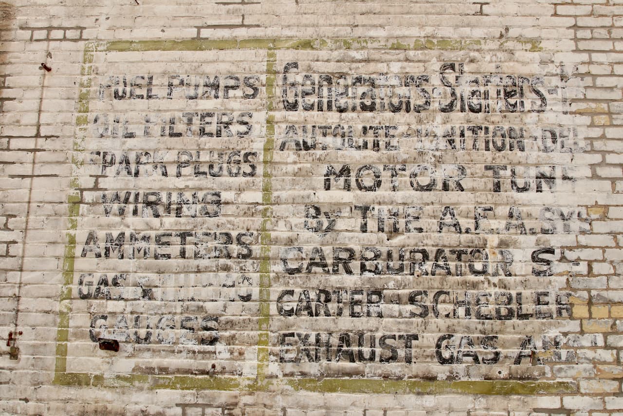 Perhaps the sign, faded by time and the elements on the east wall offers a clue to a previous use of the back part of the building?